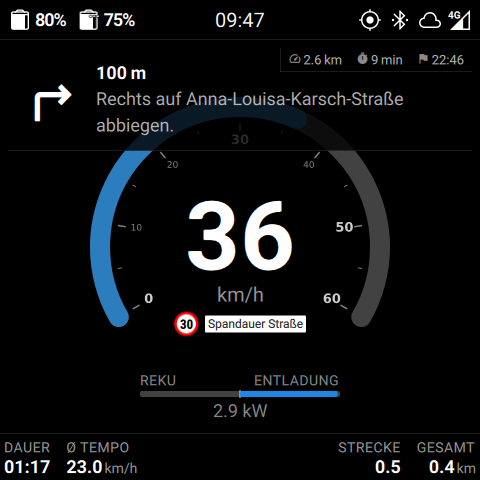 Cluster-Bildschirm im Fahrmodus mit oben eingeblendeter Turn-by-Turn-Anweisung und Karte im Hintergrund